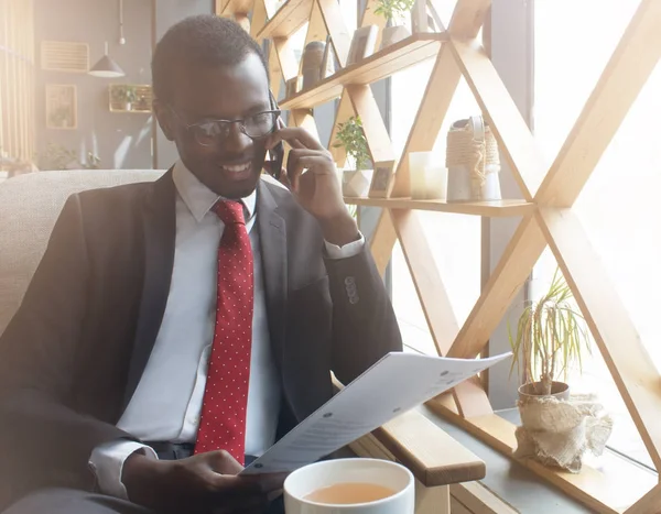 Yatay resim kafede kapalı serbest zaman harcama, iş telefonda konuşurken ve kağıtları raporları veya önemli belgelerle holding resmi kıyafetler çift erkek esmer