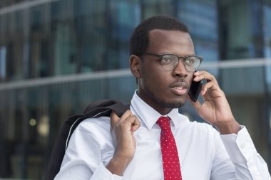 Esmer genç iş adamı beyaz resmi gömlek, kırmızı kravat ve siyah çerçeveli gözlük telefon ciddi ve yoğun yüz ifadesi ile iş konuları tartışmaya açık closeup