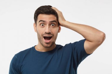 Mavi rahat giyimli genç adam oh Tanrım açık ağız, düşük fiyat ve satış, tarafından sürpriz ile bağırarak t-shirt gri arka plan üzerinde izole.