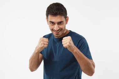 Mavi t-shirt holding emin sportif adam mücadele etmek ve kendini savunmak için onun önünde yumruklar. Onun gücü, sorunlar için hazır gösterilen yakışıklı atletik erkek
