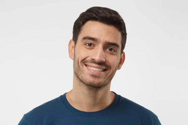 Close-up shot van de glimlachen van aantrekkelijke man blauw die t-shirt geïsoleerd op een grijze achtergrond — Stockfoto