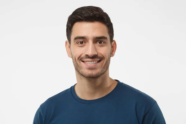 Close-up van portret van lachende knappe jongen in het blauw die t-shirt geïsoleerd op een grijze achtergrond — Stockfoto