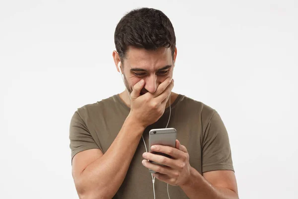 Junger Mann lacht, genießt Witze von einem Freund per SMS, erstaunt über lustige Online-Videos, isoliert auf grauem Hintergrund — Stockfoto