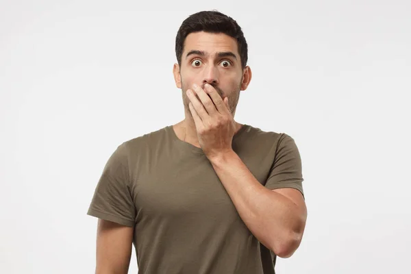 Astonished bug-eyed student covering his mouth with one hand, looking shocked. Surprised, embarrassed and confused young male showing omg emotion — Stock Photo, Image
