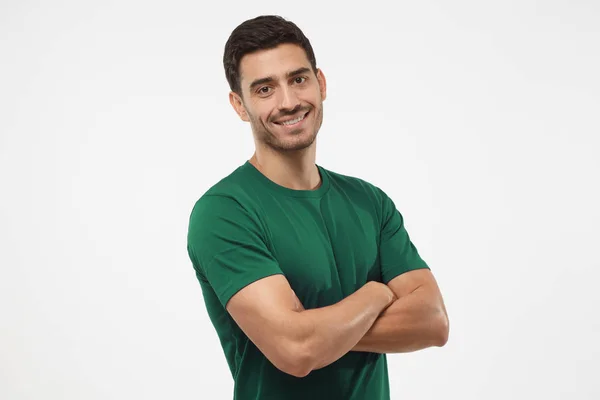 Retrato de atraente jovem desportivo macho em t-shirt verde de pé com braços cruzados isolados em fundo cinza. Treinador de fitness ou crossfit — Fotografia de Stock