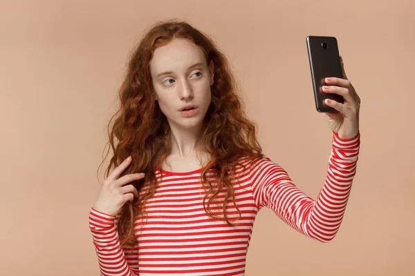 Retrato de jovem mulher ruiva atraente usando smartphone para tirar fotos de selfie e sorrir para a câmera — Fotografia de Stock