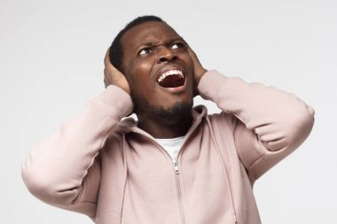 Genç yakışıklı Afrika adam bağırmak gürültülü komşular, gürültü, kulakları her iki el ile kapatma tarafından vurguladı önlemek dinleme mücadele