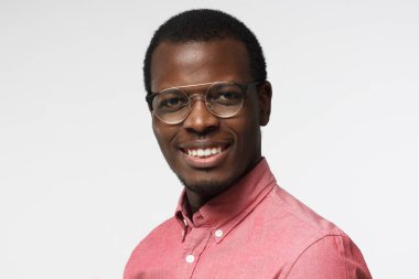 Sanki yeni fikirlerini paylaşmaya istekli mutlu dostu gülümseme gösterilen şık gözlük ile beyaz arka plan üzerinde izole yakışıklı Afrika erkek resimde rahat kıyafetler içinde yatay headshot