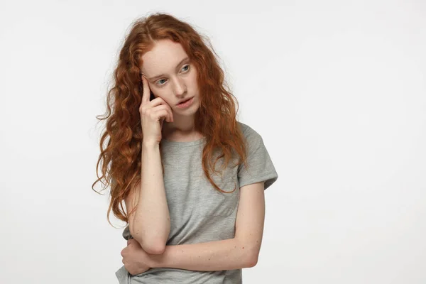 Elfáradt és fúrt vöröshajú nő a szürke póló, intett a kezével, kapcsolat, vagy egészségügyi probléma megoldásában. Kétség koncepció. — Stock Fotó