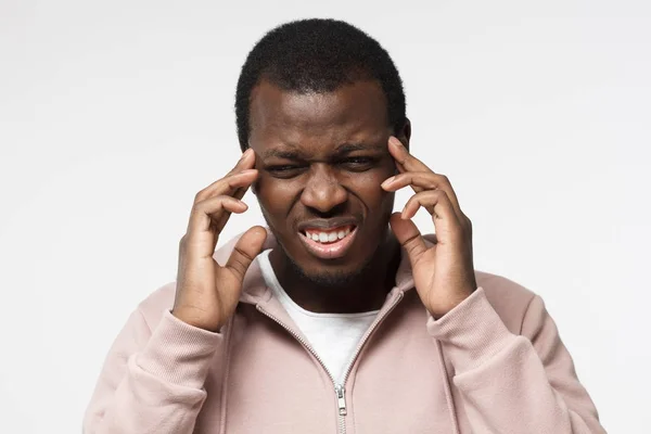 Studio foto van knappe Afrikaanse guy afgebeeld geïsoleerd op witte achtergrond in casual kleding die lijden aan ernstige hoofdpijn probeert te gaan en zich concentreren op probleem of taak aanraken van de tempels — Stockfoto