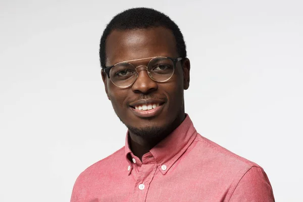 Closeup headshot van Afro-Amerikaanse ondernemer permanent in rood shirt tegen witte achtergrond, het dragen van de ronde bril, glimlachend met tevredenheid en vertrouwen tonen toewijding aan zijn bedrijf — Stockfoto