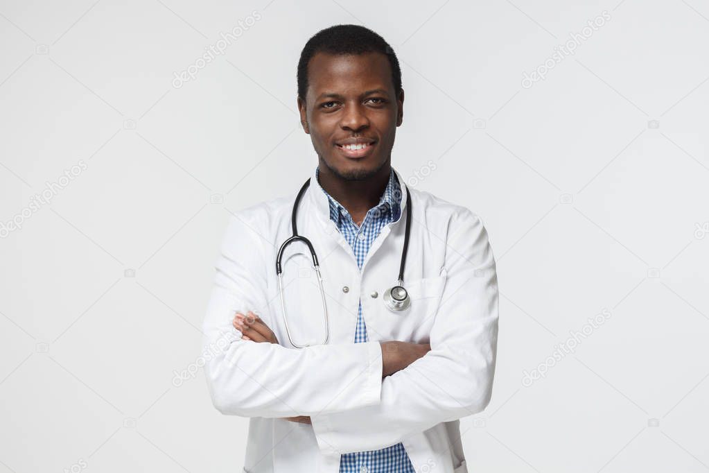 Horizontal portrait of handsome African American physician pictured isolated on white background with stethoscope around neck showing confident smile ready to help patients cope with health problems