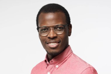 Çekici Afrika adam pembe gömlek ve gri arka plan üzerinde izole gözlük gülümseyen in atış yukarıya kapatmak