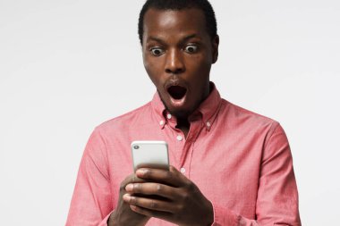 Pembe gömlekli yakışıklı genç siyah adam arıyorum smartphone, holding portresi yakından korkmuş ve kýsa mesaj veya e-posta okuma kafası karışık