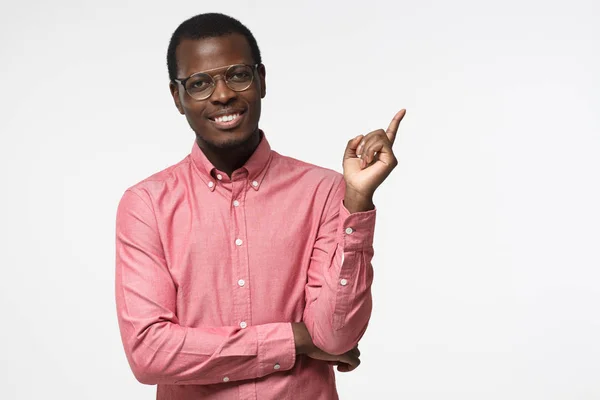 Aantrekkelijke jonge africna man in roze shirt recht met zijn vinger wijzend geïsoleerd op een grijze achtergrond — Stockfoto