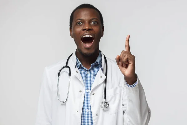 I have an idea! African doctor keeping finger pointed upwards, showing something above his head, making gesture with index finger. Eureka, solution sign concept