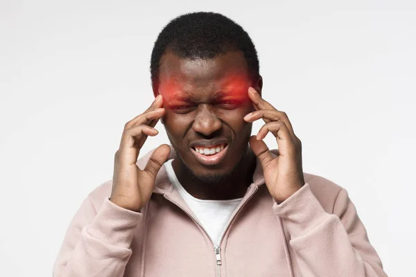 Imagen de estudio de chico africano guapo en la foto aislado sobre fondo blanco en ropa casual que sufre de dolor de cabeza severo tratando de hacer frente a ella y concentrarse en el problema o la tarea de tocar las sienes —  Fotos de Stock