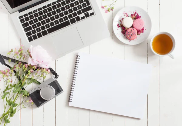 Livro de esboços em branco. Feminino flat lay espaço de trabalho com laptop, xícara de chá, macarons e flores em mesa de madeira branca. Vista superior mock up . — Fotografia de Stock