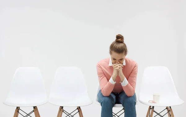 Giovane donna seduta in fila o in coda, cercando stressato, mettendo le mani insieme come se stesse pregando con gli occhi chiusi per superare la depressione — Foto Stock