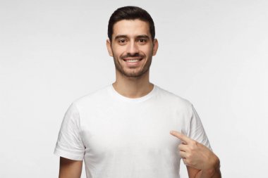 İşaret parmağı, kopya alanı için reklam, onun boş Beyaz tişört gösteren gülümseyen güzel adam gri arka plan üzerinde izole