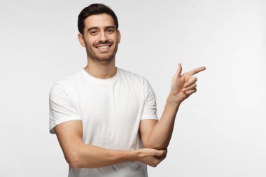 Beyaz t-shirt şu gri arka plan üzerinde izole parmağıyla işaret içinde genç adam