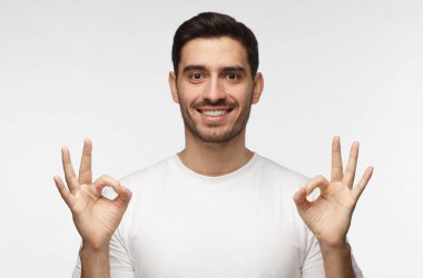 İyi görünümlü bir adam gri arka plan gülümseyen izole ve iki elle iyi işaret gösteren, adresleme izleyici ile tavsiye deneyim pozitif paylaşımı
