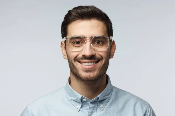 Close-up shot van de glimlachen van aantrekkelijke zakenman in blauw shirt en trendy trasparent brillen geïsoleerd op een grijze achtergrond — Stockfoto