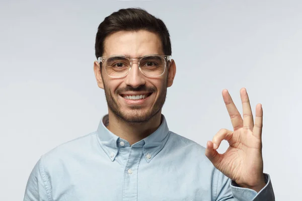 Jonge man gelukkig kijken, glimlachen, gebaren, tonen Ok teken, tonen Ok-gebaar met zijn vingers. Lichaamstaal concept — Stockfoto