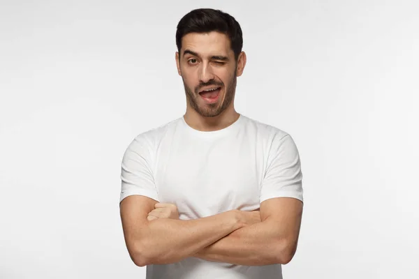 Studio shot of good looking man isolated on grey background looking enterprising and enthusiastic, winking friendly as if inviting to adventure or recommending good benefit — Stock Photo, Image