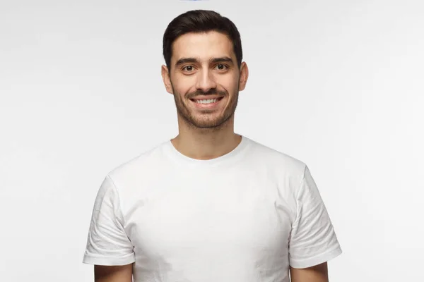 Fiatal, mosolygós, optimista ember üres fehér póló állandó elszigetelt világos szürke háttér — Stock Fotó
