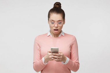 Onun akıllı telefon, medya içeriği Web'den tarafından etkilendim sergilenen seyir gri arka plan üzerinde izole kadın portresi, heyecanlı