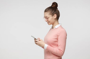 Genç çekici erkek görünümlü ve manifatura süre ile smartphone, cep telefonuyla arkadaşı gri arka plan üzerinde izole.