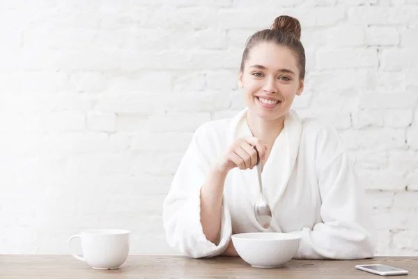 Jovem tomando café da manhã na cozinha na sala do loft branco, comendo cereais e bebendo café. Espaço de cópia para o seu texto publicitário — Fotografia de Stock