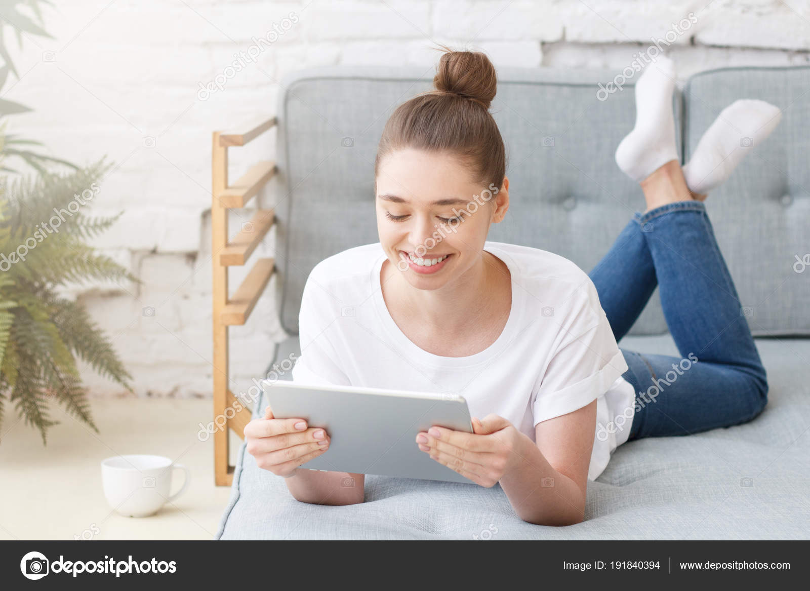 Junge Frau im Bett liegend, beim Lesen eines Buches 