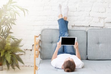 Genç kadın kanepede döşenmesi, rahatlatıcı, onun tablet bir şey izliyor