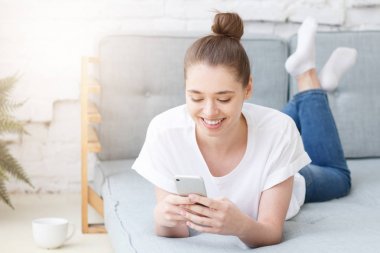 Akıllı telefon kullanan mutlu neşeli gülümseyen genç kadın