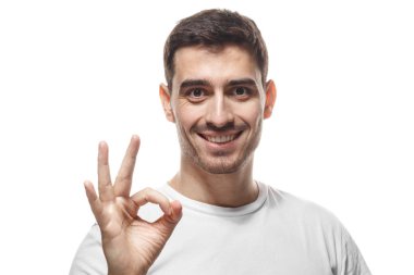 Ok işareti, tamam-jest parmaklarıyla gösterilen boş tshirt gülümseyerek mutlu göz olan beyaz arka plan üzerinde izole el hareketi, genç adam. Beden dili kavramı