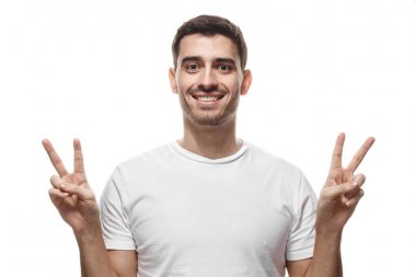 Genç erkek iyimser gülümseme ile boş tshirt beyaz zemin üzerine izole kapalı portresi, gösteren zafer dostu arıyorum her iki el ile oturum ve istekli hoş geldiniz ve iletişim