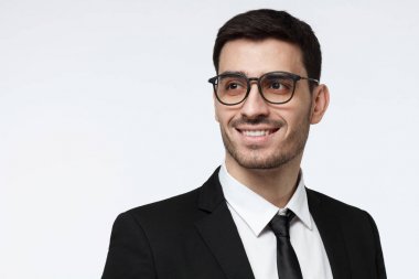 Closeup çekim genç şirket Danışmanı sol, olumlu ve kendine güvenen için seyir dişlek açık gülümseme gösterilen trendy gözlük resimde izole üzerinde gri arka plan giyen resmi siyah takım elbise,'ın