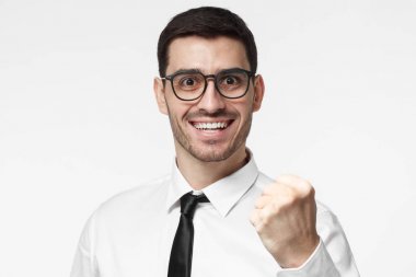 We did it! Corporate office goal success concept. Business man shouting while his team succeed, raised his fist in victory gesture, isolated on grey background clipart