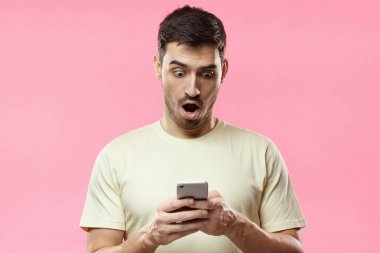Genç adam, pembe arka plan izole portresi, sergilenen bu onun akıllı telefon, medya içeriği Web'den tarafından etkilendim heyecanlı arıyorum