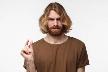 Genç sakallı adam elleriyle unpleased yüz ifadesi ile küçük boyut gösterilen kahverengi tshirt içinde gesticulates. Çok küçük! 