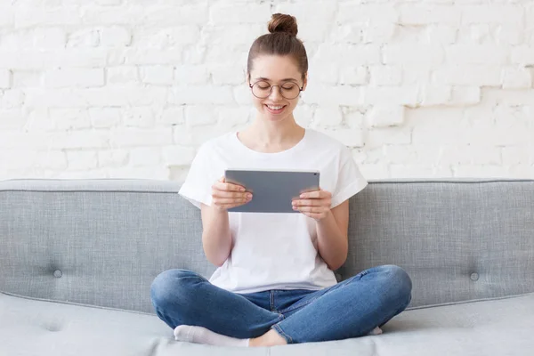 Электронная коммерция женщина-клиент сидит дома на диване с планшетом, используя его для покупок в Интернете, широко улыбаясь — стоковое фото