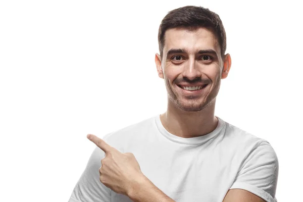 Hombre guapo en camiseta blanca apuntando a la izquierda con el dedo aislado — Foto de Stock