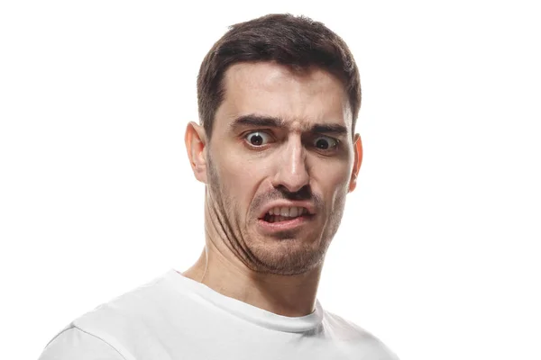 Disguting! Shocked young man looking at something unpleasant and bad, isolated on gray background. Negative emotion concept — Stock Photo, Image