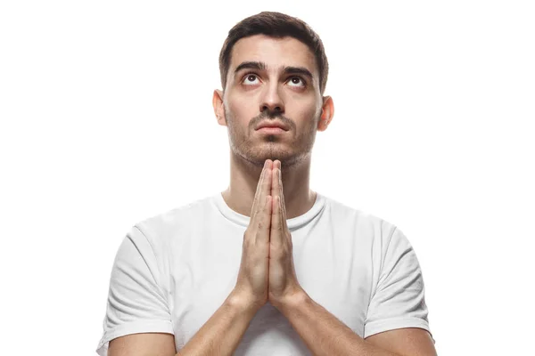 Picture of young man dressed casually isolated on white background, having put hands together in prayer or meditation, looking up, dreaming, bagging — Stock Photo, Image