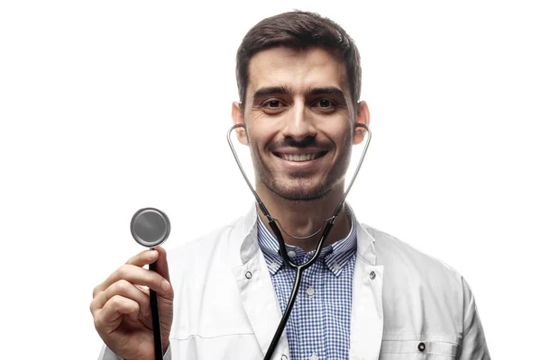 Retrato de homem médico segurando estetoscópio, olhando para a câmera e sorrindo isolado no fundo branco — Fotografia de Stock