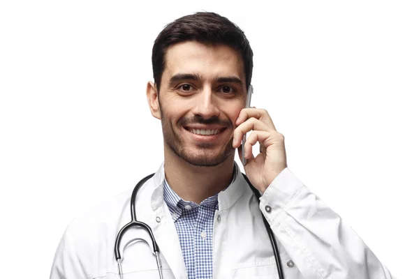 Primer plano de hombre guapo médico aislado sobre fondo blanco hablando en el teléfono inteligente, sonriendo positivamente —  Fotos de Stock