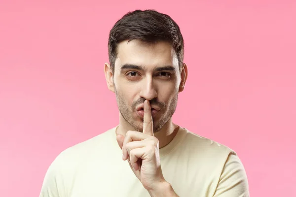Close up shot of handsome tricky man with shh gesture, asking for silence or to be quiet, isolated on pink background — Stock Photo, Image