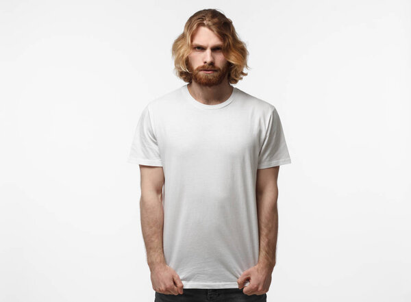 Serious brutal man in blank white tshirt isolated on grey background